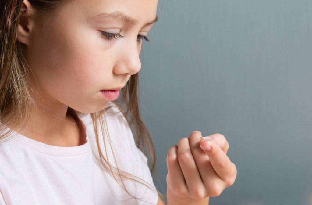 Young girl carefully holding a contact lens, preparing to apply it.