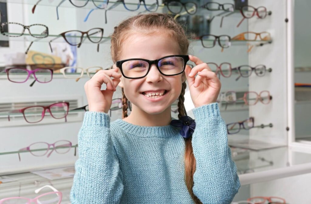 A smiling child tries on a new pair of glasses.